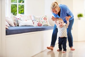 Mother Helping Young Son As He Learns To Walk